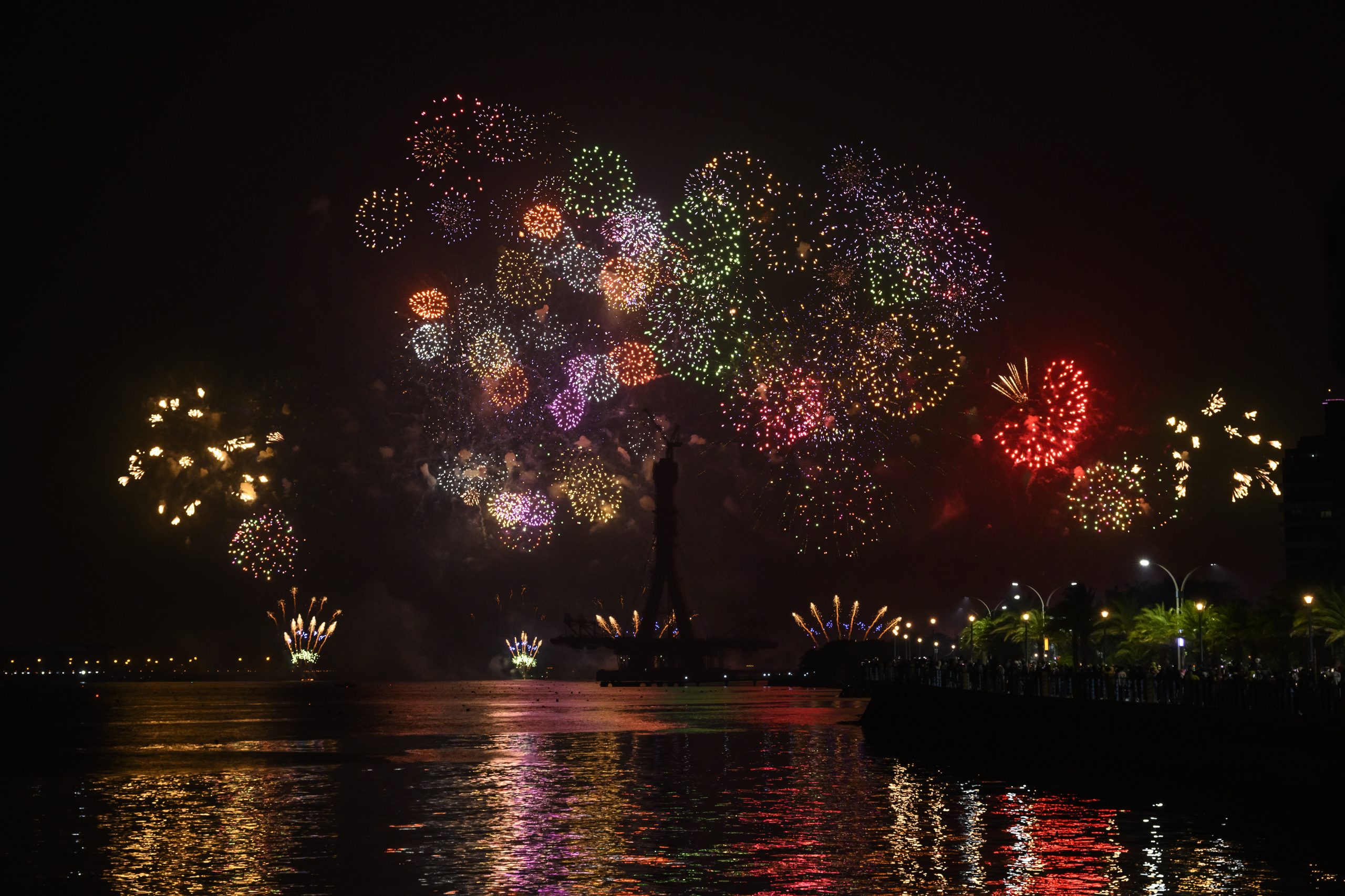 Multi-coloured New Year fireworks over a river with reflections on the water