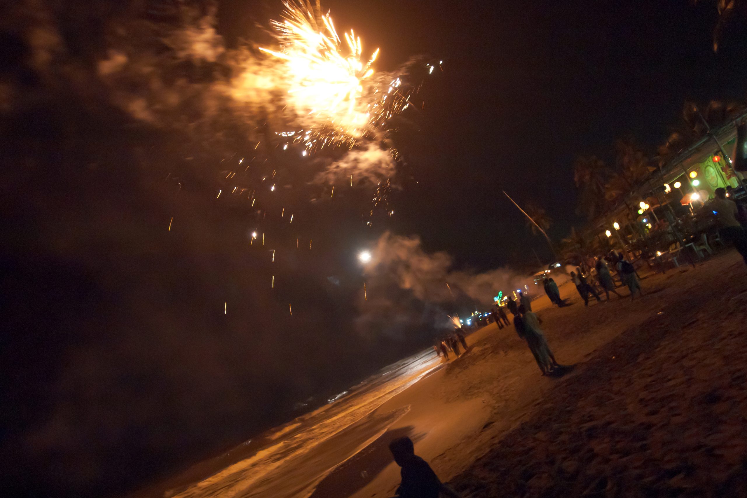 Fireworks bursting over the beach at a New Year's Eve night party