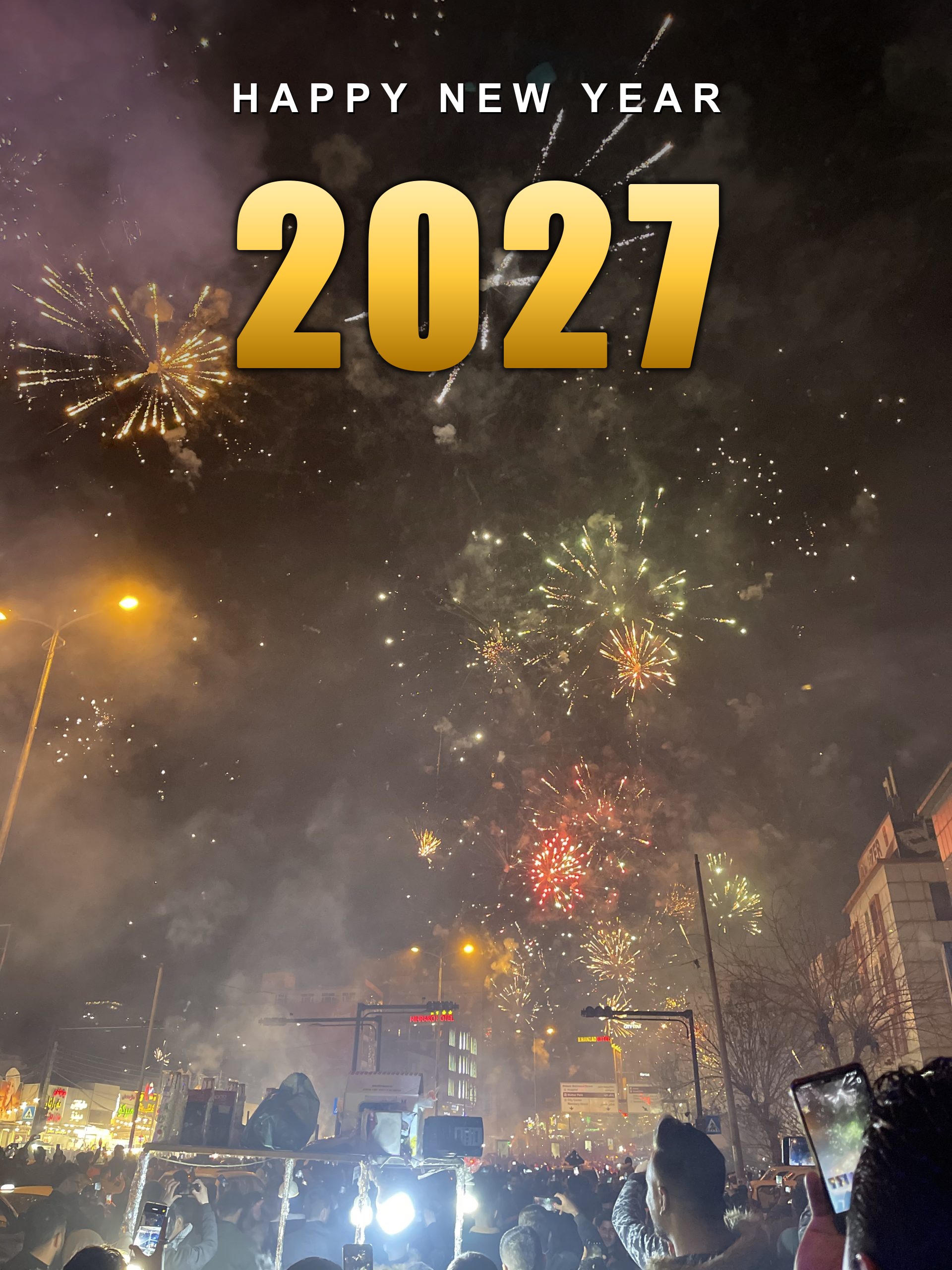 Happy New Year 2027 in gold lettering over a street fireworks crowd, vertical