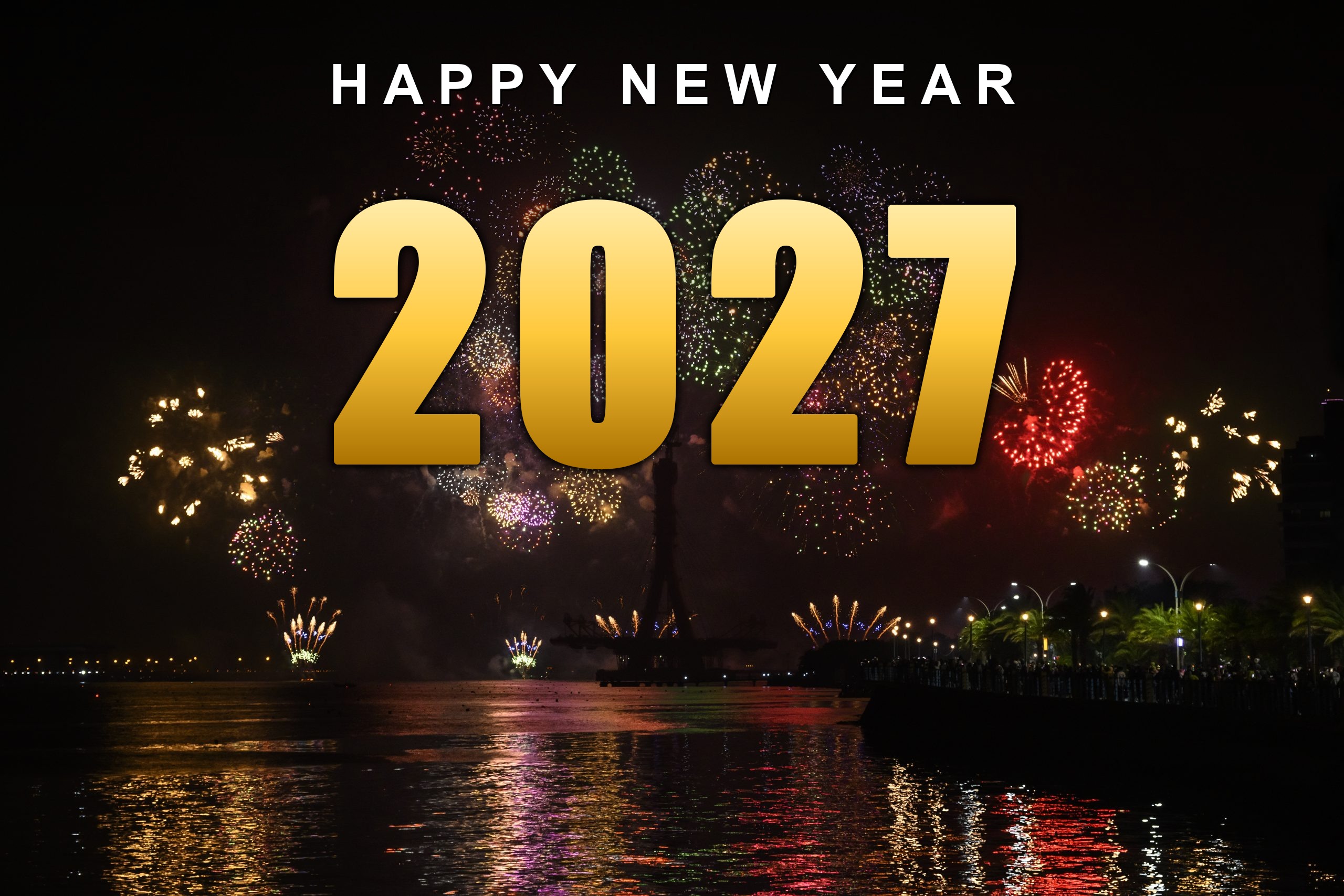 Happy New Year 2027 in gold lettering over river fireworks with reflections